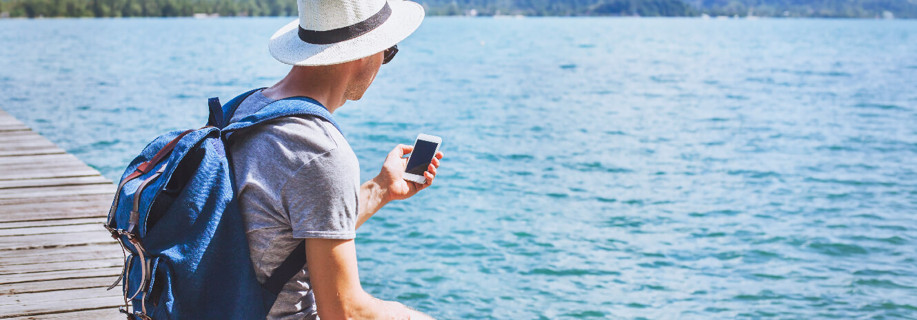 guy siting on dock looking at mobile phone